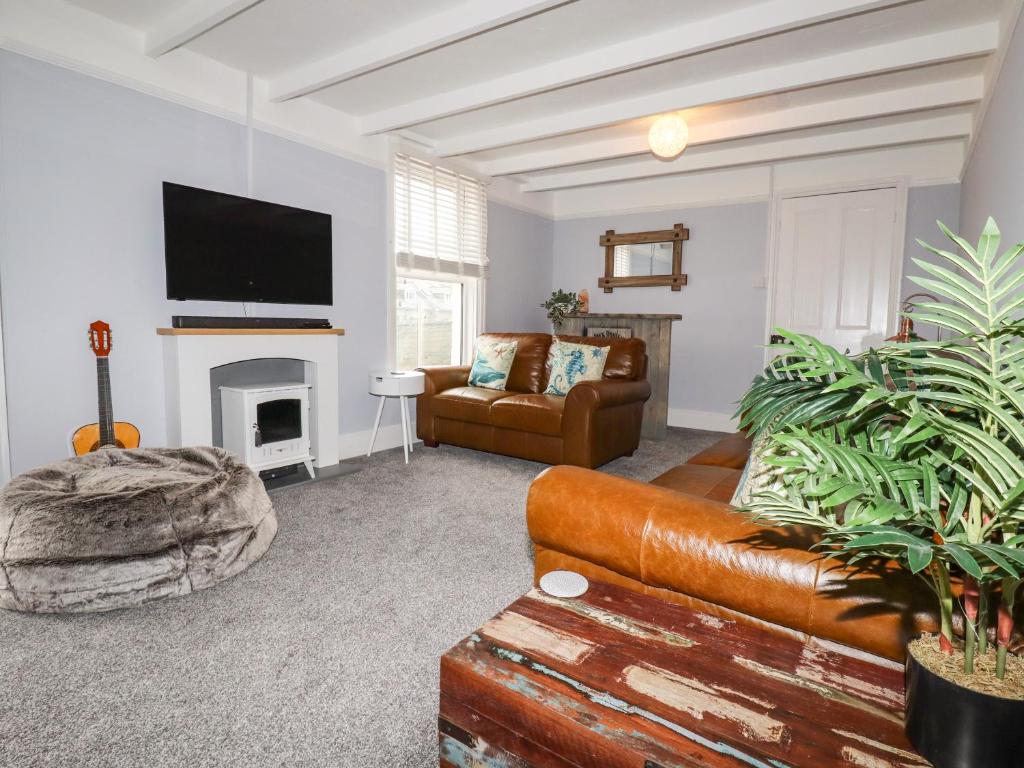 a living room with a couch and a fireplace at The Old Bark House No 3 in Mevagissey