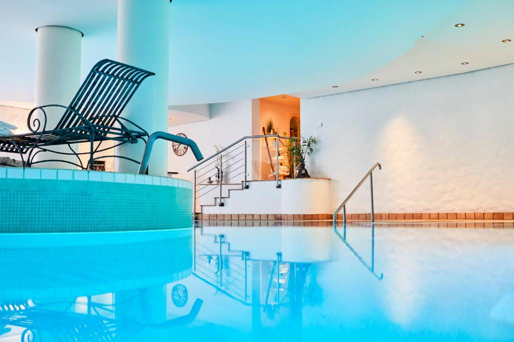 a swimming pool with two chairs and a staircase in a house at Hotel Landhaus an de Dün in Sankt Peter-Ording