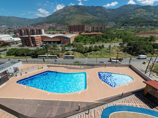 a large swimming pool in a city with a mountain at Arriendo hermoso y amplio apartamento amoblado y con piscina, frente a la estación Niquia y al centro comercial puerta del norte. in Bello