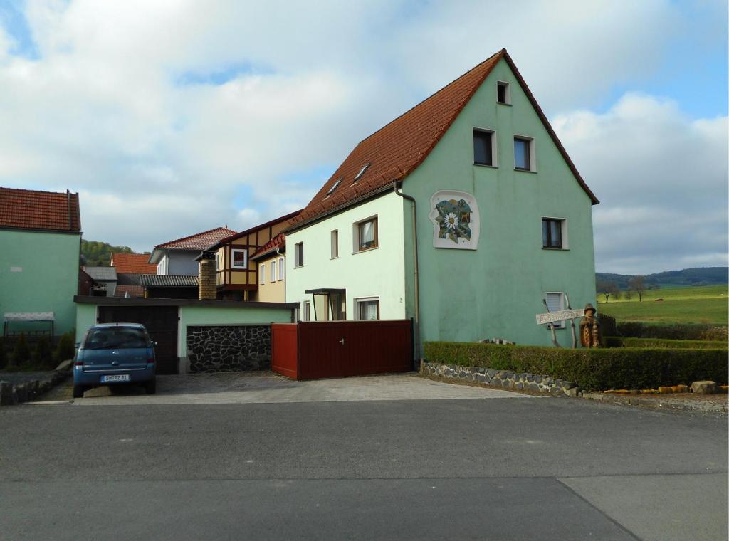 a white and green house with a car parked in front at Ferienhaus Kämpf in Kaltennordheim