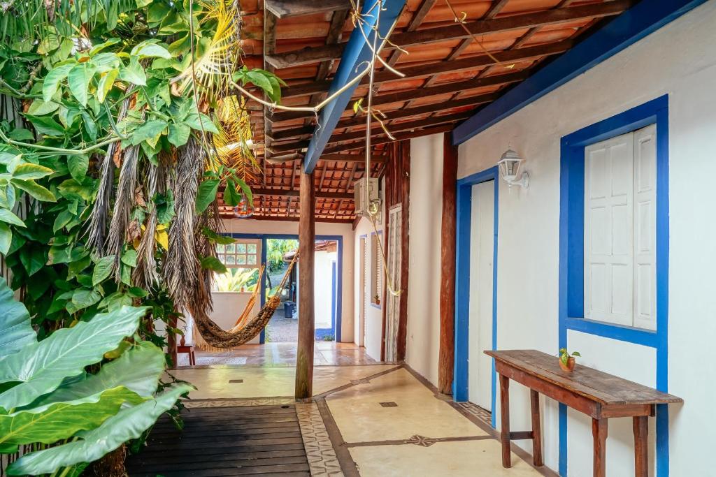 Tropicália Hostel e Pousada في إيتاكاري: ممر منزل فيه مقاعد ونباتات
