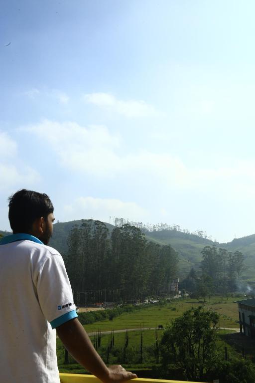 un hombre volando una cometa sobre un campo verde en MSP Amma Cottage en Munnar