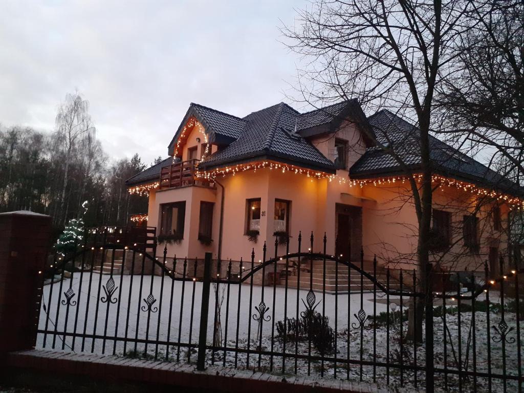 a house with a fence with lights on it at Noclegi Pod Dębem, Pulandia Brzózki in Brzózki