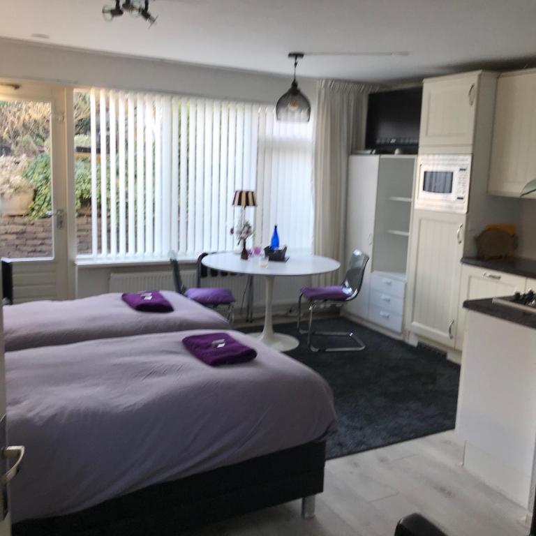 a bedroom with a bed and a table and a kitchen at Villa 't Haasduin in Wijk aan Zee