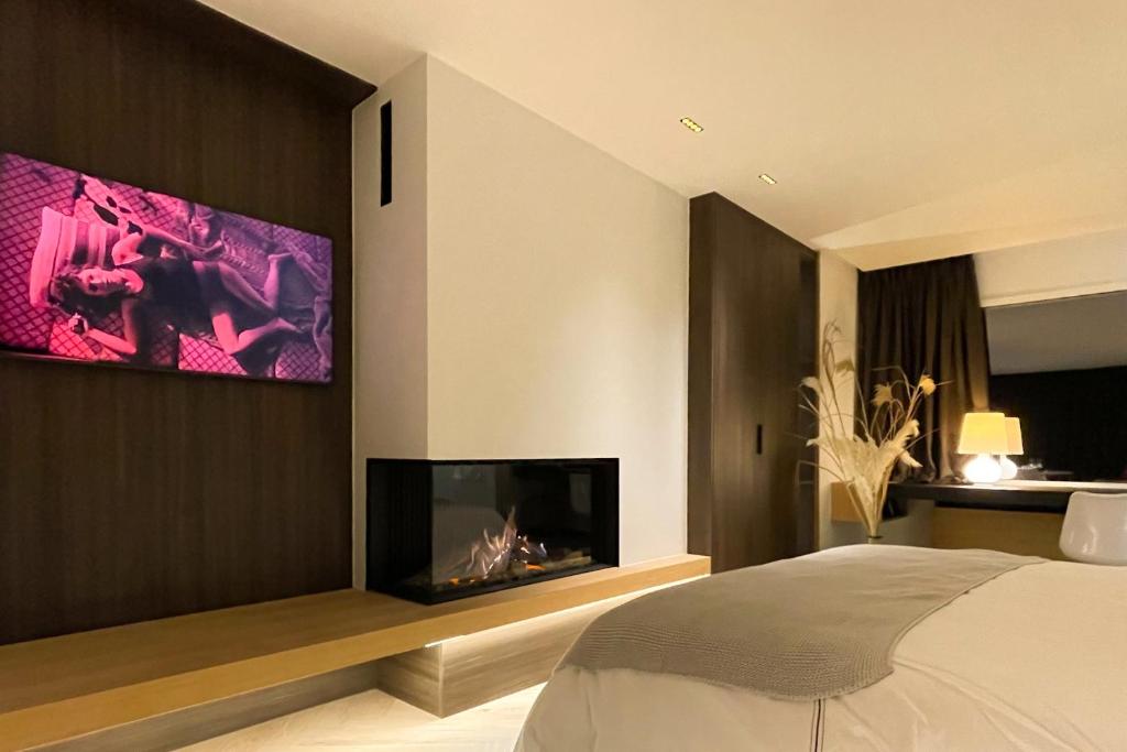 1 dormitorio con chimenea y TV en la pared en Le19 Suite Georges & Lucy en Namur