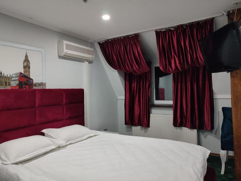 a bedroom with a bed with a red headboard and curtains at Leoton Chernivtsi in Chernivtsi