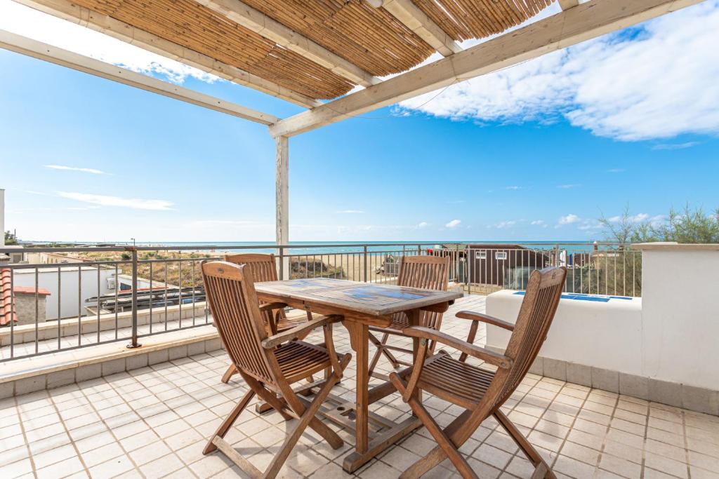 una mesa y sillas en un balcón con vistas al océano en alloggio turistico VistAmare (il guardiano del faro) en Focene