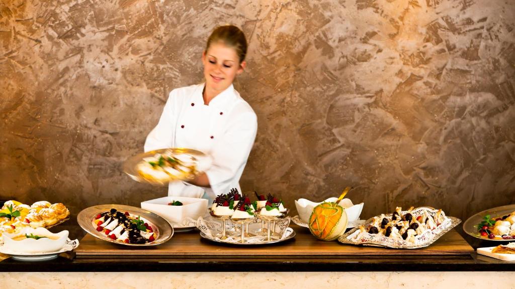 a chef standing behind a buffet of desserts at Superior Hotel Tirolerhof - Zell am See in Zell am See