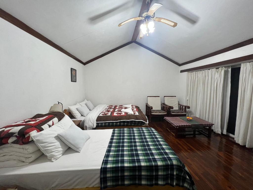 una camera da letto con due letti e un ventilatore a soffitto di ES Deurali Resort a Pokhara