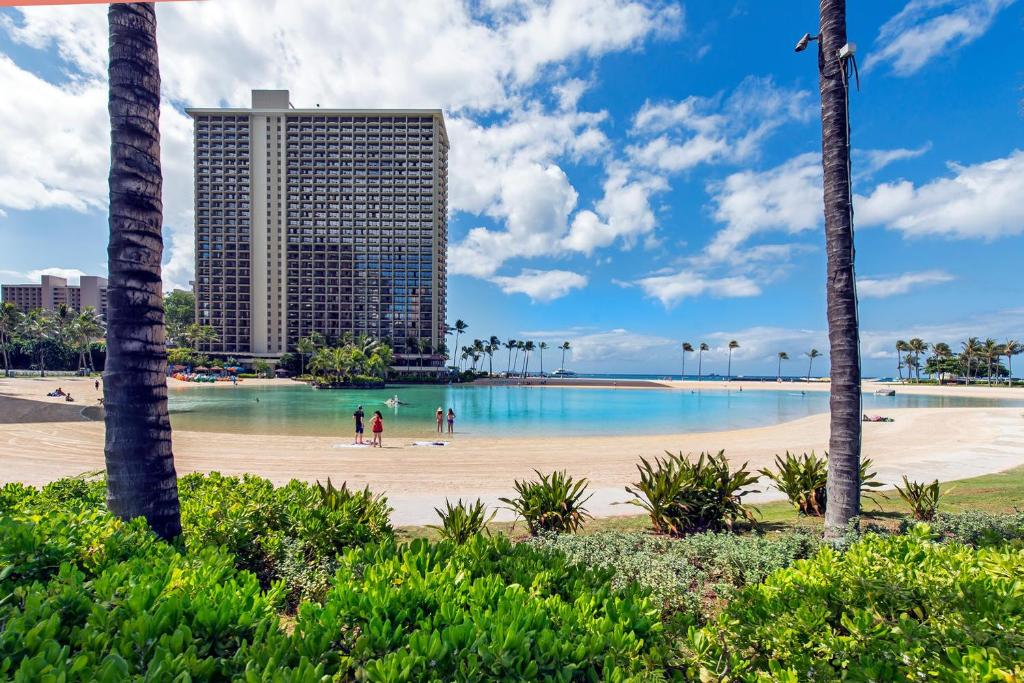 einen Strand mit Palmen und Gebäuden im Hintergrund in der Unterkunft Ilikai Tower 701 City View 1BR in Honolulu