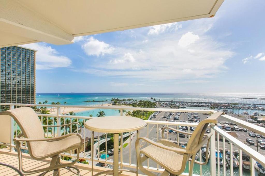 a balcony with a table and chairs and a view of the ocean at Ilikai Tower 943 Yacht Harbor View 2BR in Honolulu