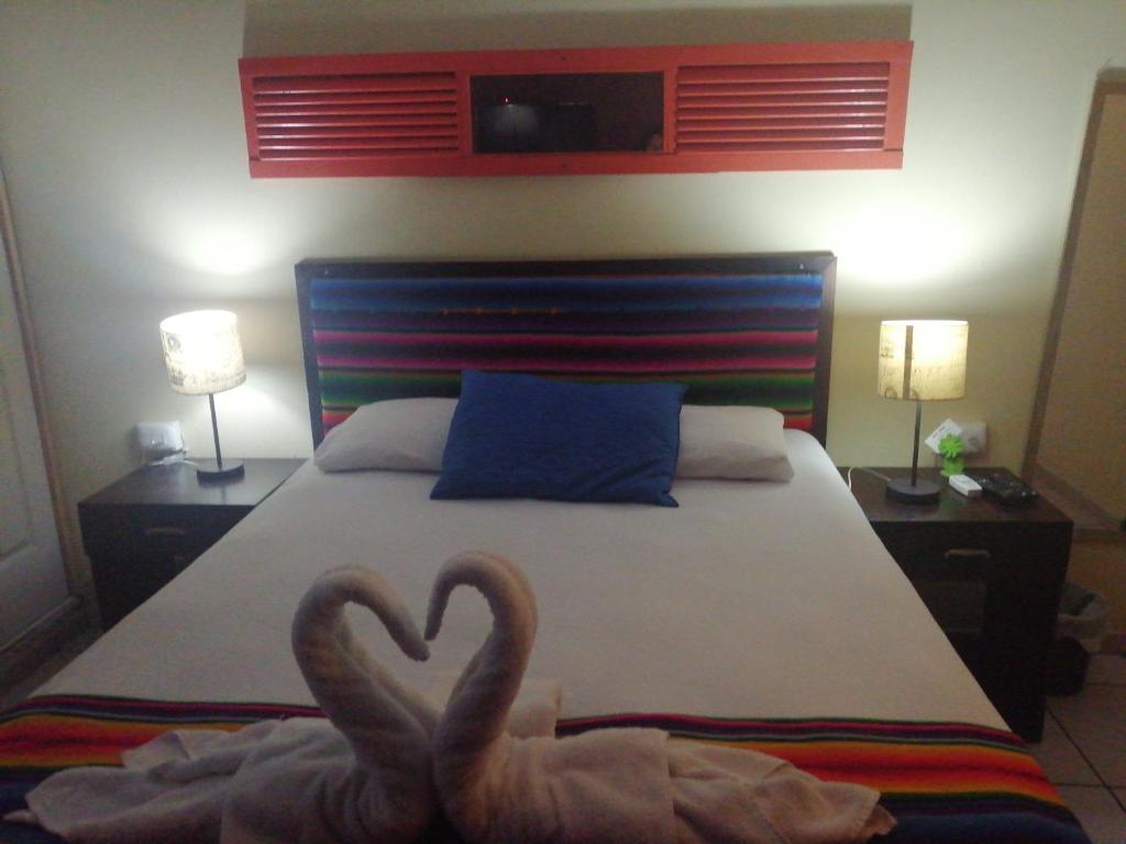 two swans sitting on a bed in a bedroom at Hotel Antiguo in Antiguo Cuscatlán