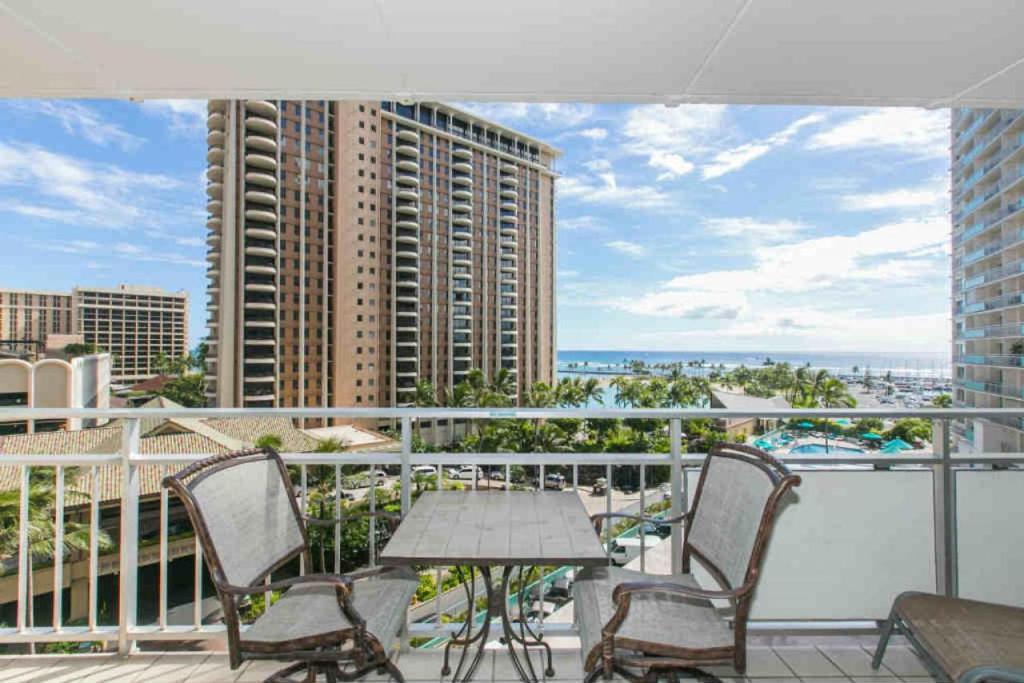 a balcony with chairs and a table and a view of a city at Ilikai Tower 618 Lagoon View 1BR in Honolulu