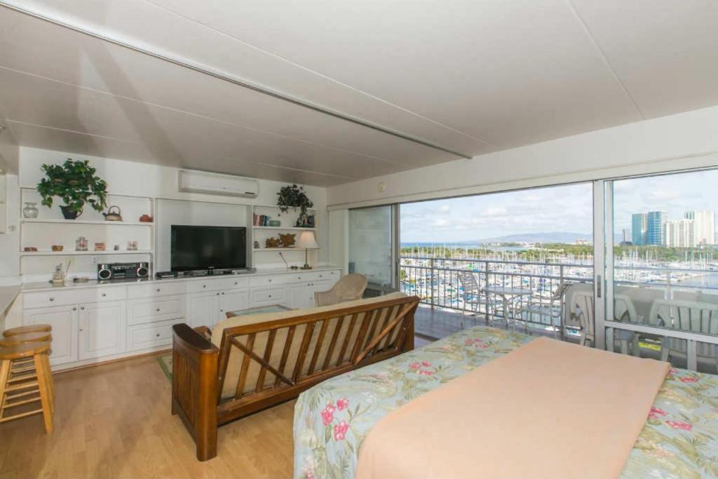 Schlafzimmer mit einem Bett, einem TV und einem Balkon in der Unterkunft Ilikai Tower 839 Yacht Harbor View 1BR in Honolulu