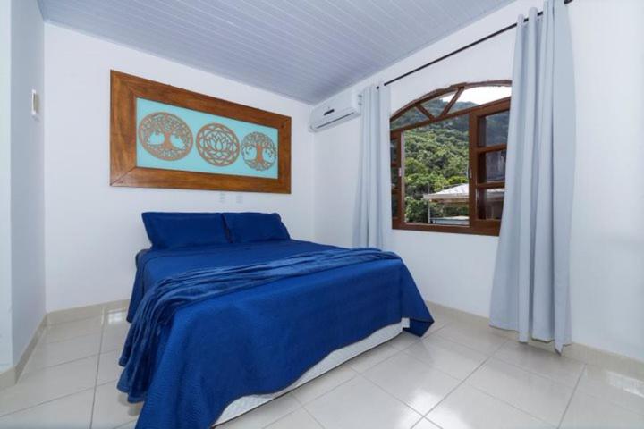 een slaapkamer met een blauw bed en een raam bij Recanto da Conceição in Bombinhas