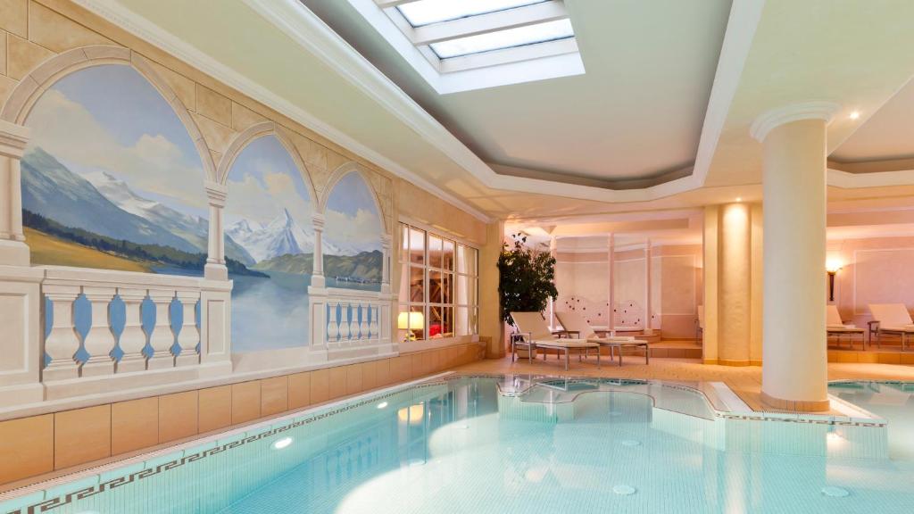 a large swimming pool in a building with a skylight at Superior Hotel Tirolerhof - Zell am See in Zell am See