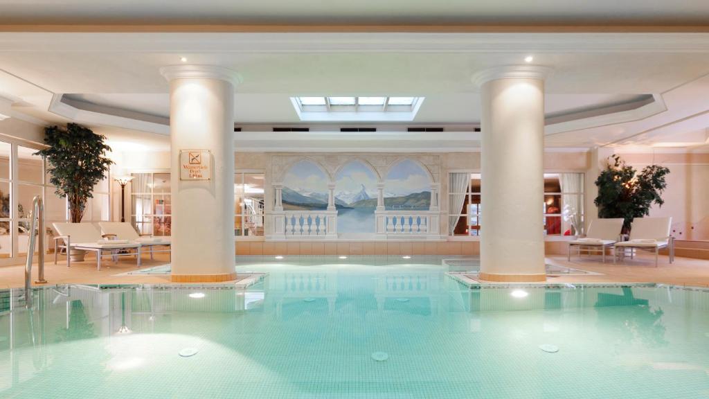 a large swimming pool in a hotel lobby with columns at Superior Hotel Tirolerhof - Zell am See in Zell am See