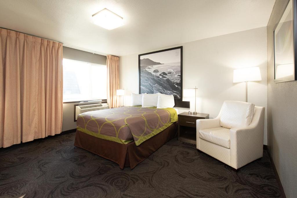 ein Hotelzimmer mit einem Bett und einem Stuhl in der Unterkunft Super 8 by Wyndham Eureka in Eureka