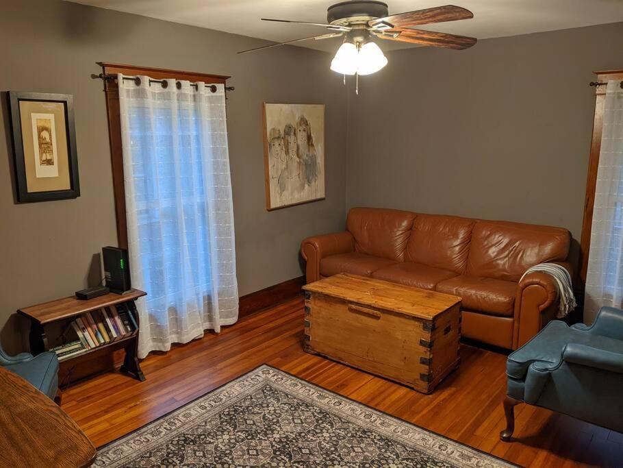 a living room with a leather couch and a table at Large Bakery Apartment - Central Downtown Location in Fredonia