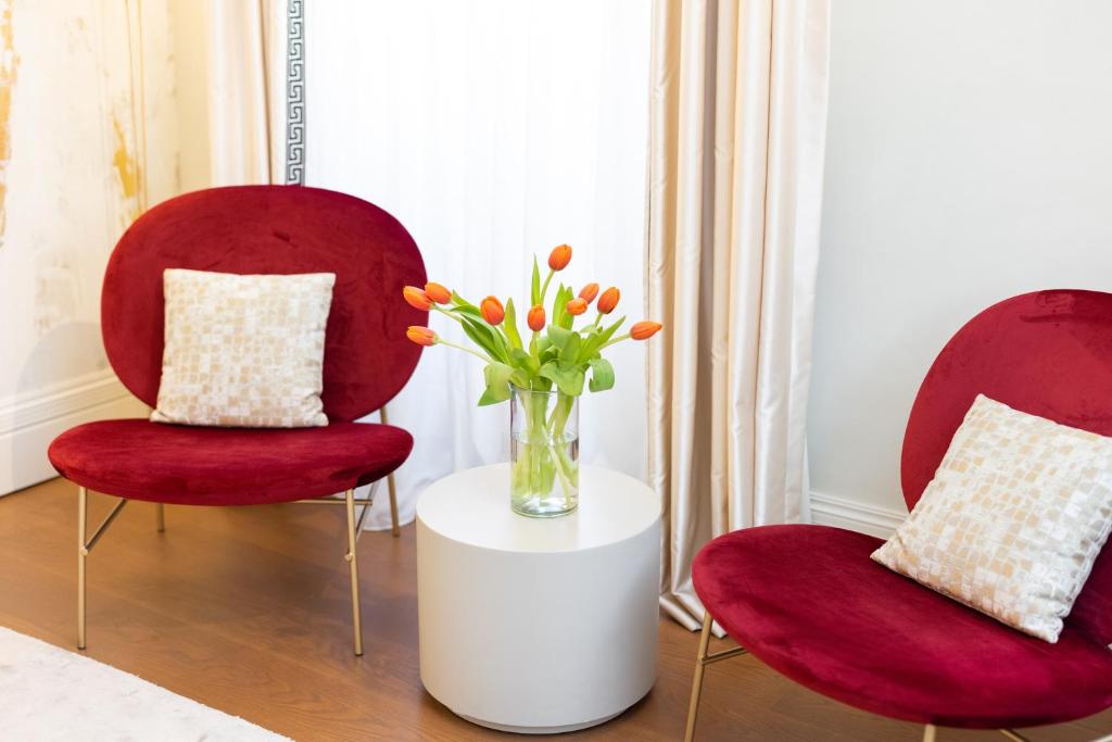 two red chairs with a vase of flowers on a table at Castellano Hotel & Suites in Nafplio