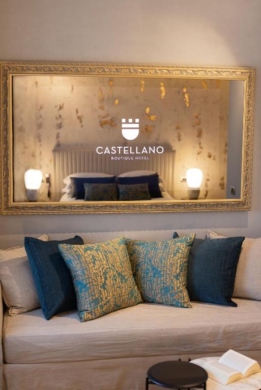 a mirror on the wall above a couch with pillows at Castellano Hotel & Suites in Nafplio