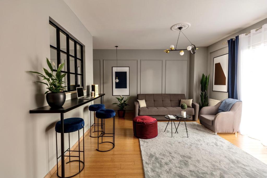a living room with a couch and a table and stools at Etern Stays - Urban Apartment in Pristina