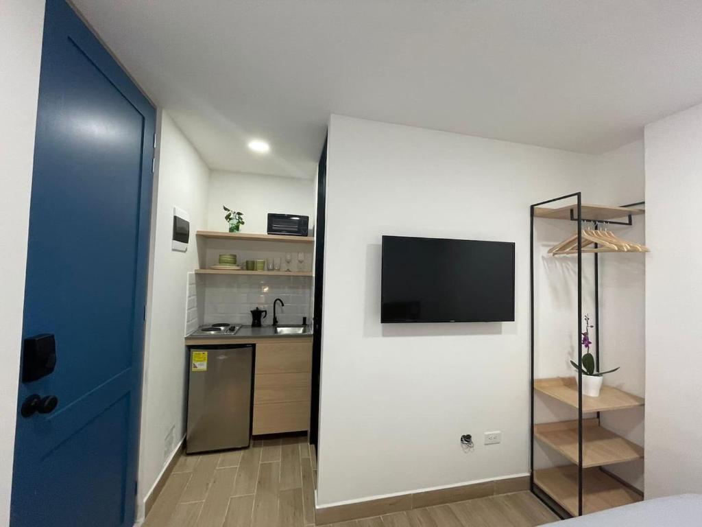 um quarto com uma parede branca e uma televisão de ecrã plano em 80Cooliving Medellín em Medellín