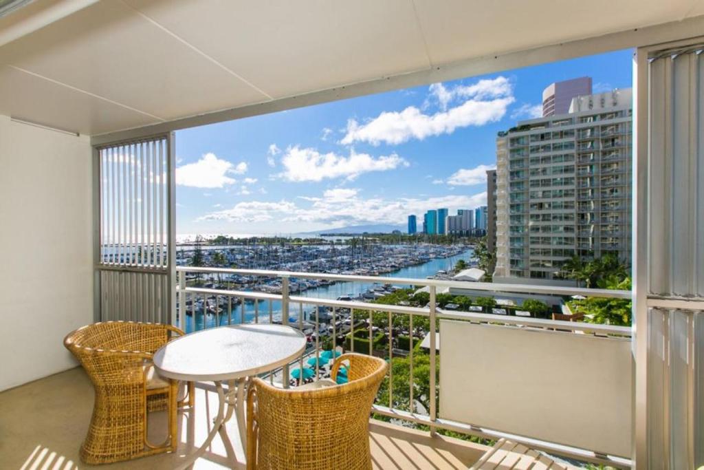 a balcony with a table and chairs and a view of a city at Ilikai Tower 735 Yacht Harbor View 1BR in Honolulu