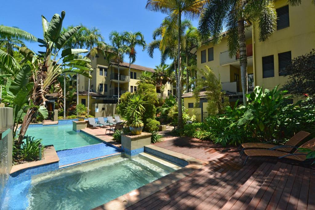 a patio with a pool, lawn, and patio furniture at Reef Club Resort in Port Douglas