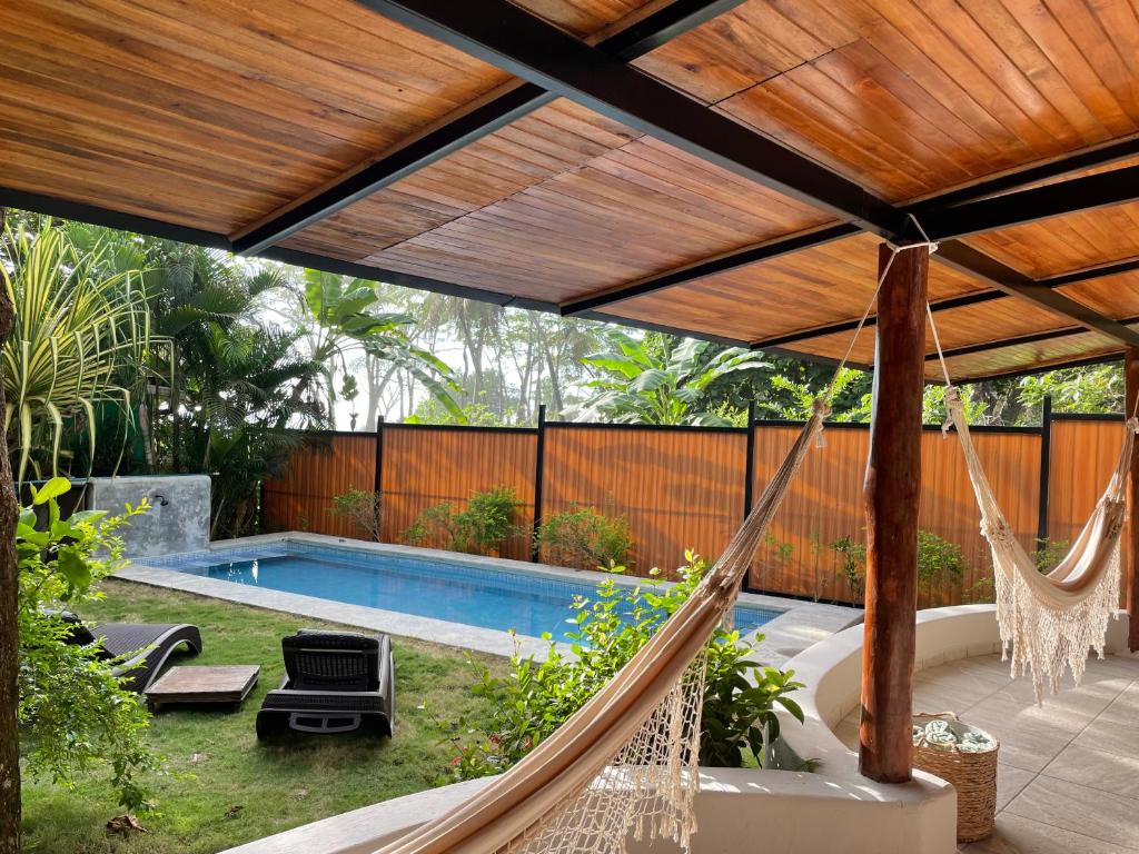 a patio with a hammock and a swimming pool at Beach Villa S in Santa Teresa Beach