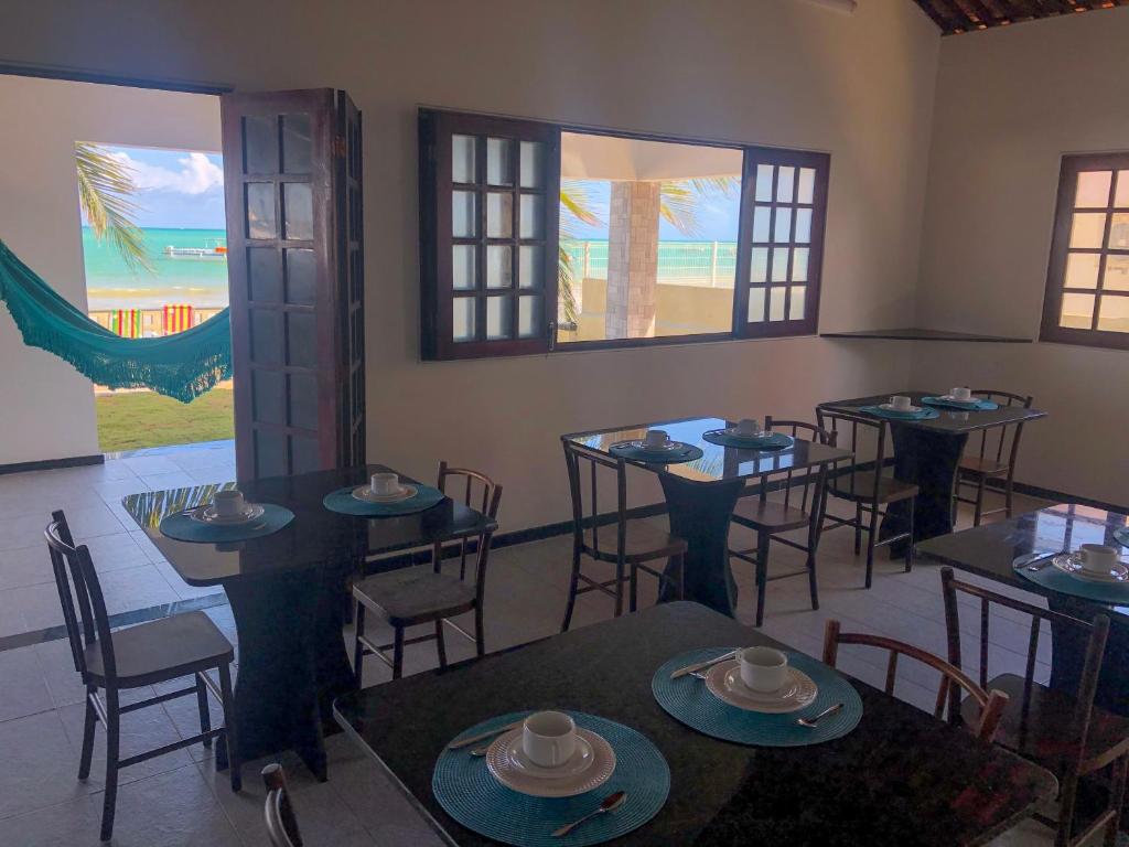 a dining room with tables and chairs and windows at Pousada La Riviera - Pé na areia e Passeios em Maragogi in Maragogi