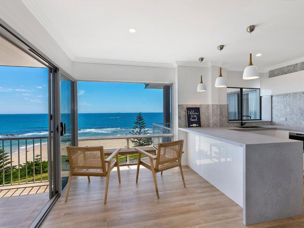 a kitchen and dining room with a view of the ocean at Dolphin Court Penthouse in The Entrance