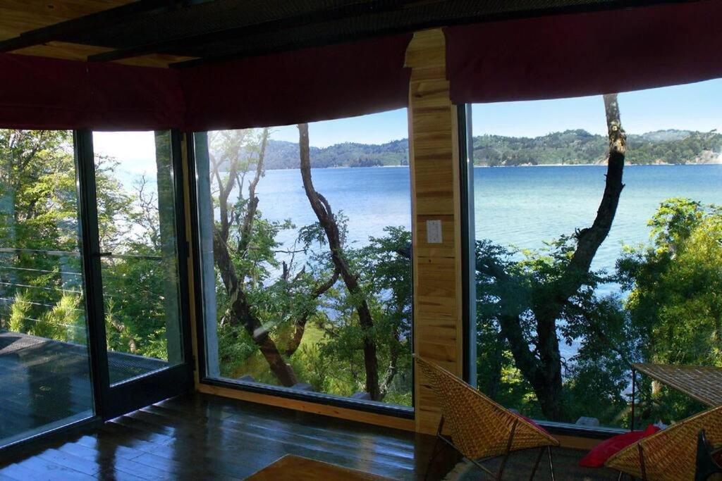 a room with large windows looking out at the water at La casa providencia - Costa del lago in Villa Pehuenia