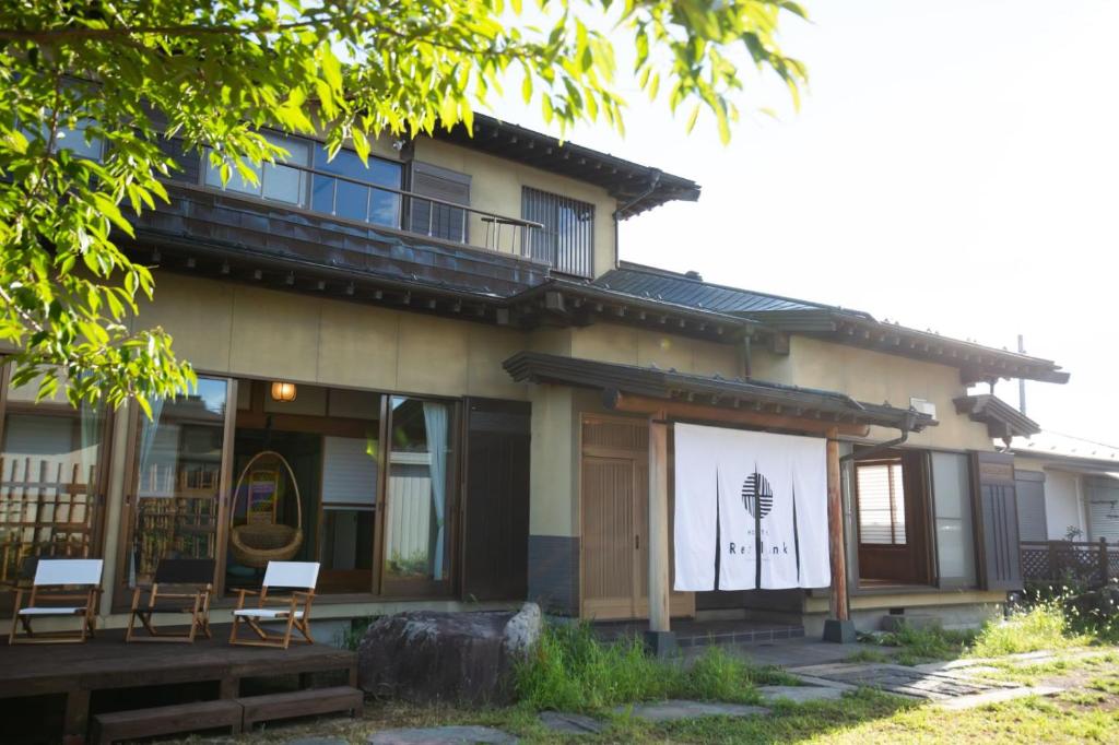 un edificio con porche y sillas delante de él en 古民家再生ホテル　Relink en Fujiyoshida