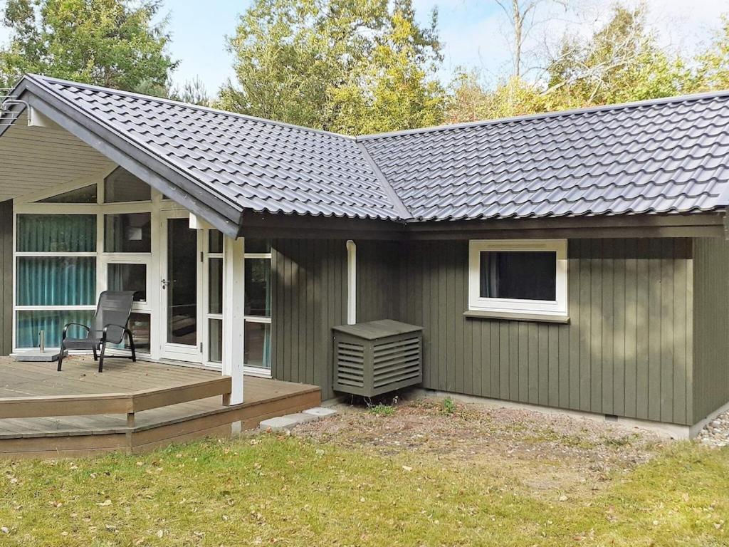 een groen huis met een veranda en een terras bij 6 person holiday home in Frederiksv rk in Frederiksværk
