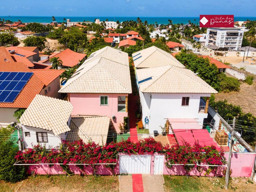 a group of houses with flowers and the ocean at Hotel Vila das Dunas Cumbuco in Cumbuco
