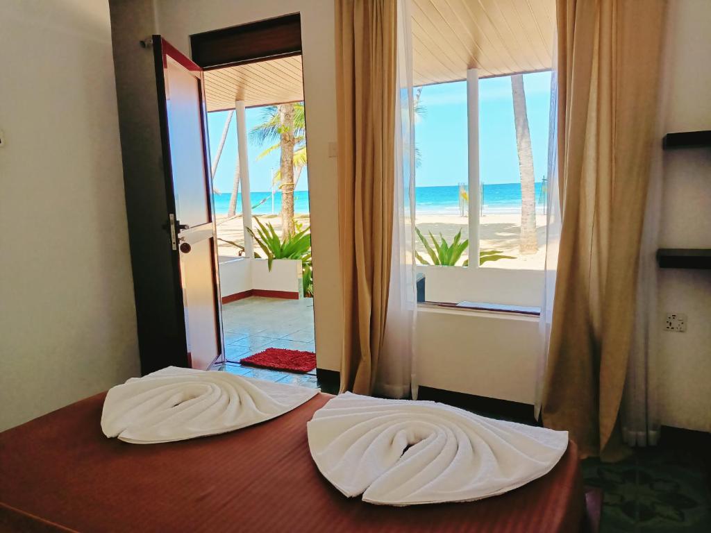 a bedroom with a bed with a view of the beach at French garden Pragash Beach Hotel in Trincomalee