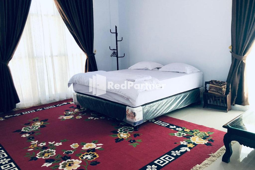 a bed in a room with a red rug with flowers on it at Wisma Suci Syariah Polewali Mandar Mitra RedDoorz in Matakali