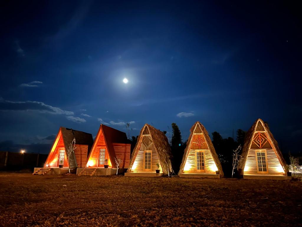 Los Alamos Cabañas & Glamping Yecapixtla في Yecapixtla: مجموعة من المنازل الخشبية مضاءة ليلا