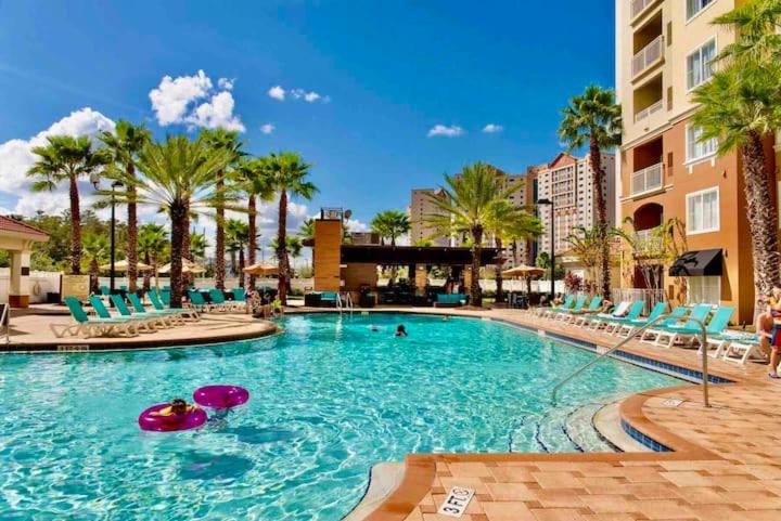 a large swimming pool with blue chairs and palm trees at Premier Resort Condos Near Disney & Universal in Orlando