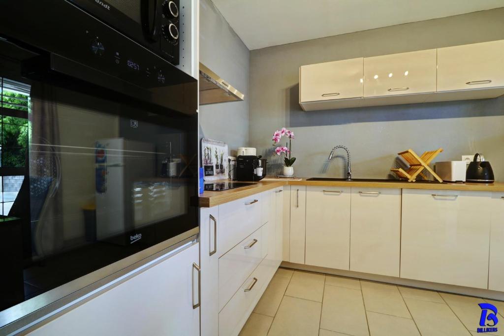 a kitchen with white cabinets and a black appliance at Appartement LES CHARMES DU NORD, classé 4 étoiles, rez-de-chaussée, jardin, 4 personnes, Sainte Clotilde, Saint Denis in Sainte-Clotilde