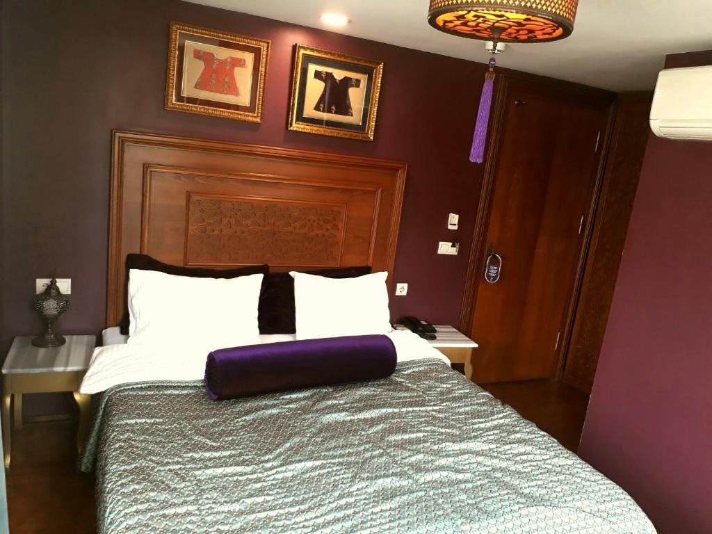 イスタンブールにあるMerial Hotel Sultanahmetのベッドルーム1室(紫色の枕が付いたベッド1台付)