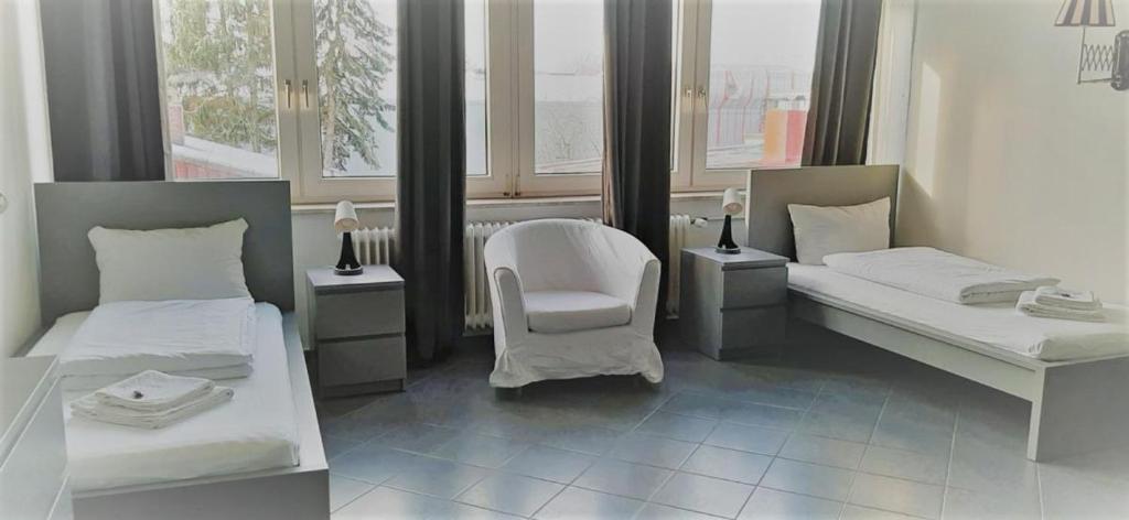 Zimmer mit 2 Betten, einem Stuhl und Fenstern in der Unterkunft Mehrbett-Apartment 3 Citynah, einfache Ausstattung in Hamburg