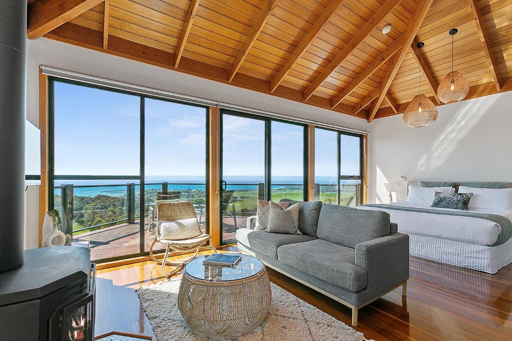 a living room with a couch and a bed and windows at Point of View Villas in Apollo Bay