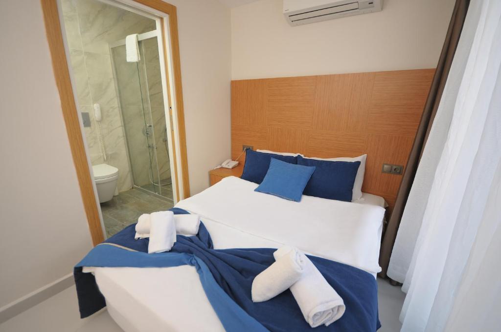 a bedroom with a bed with blue and white pillows at Saatlı Hotel in Çeşme