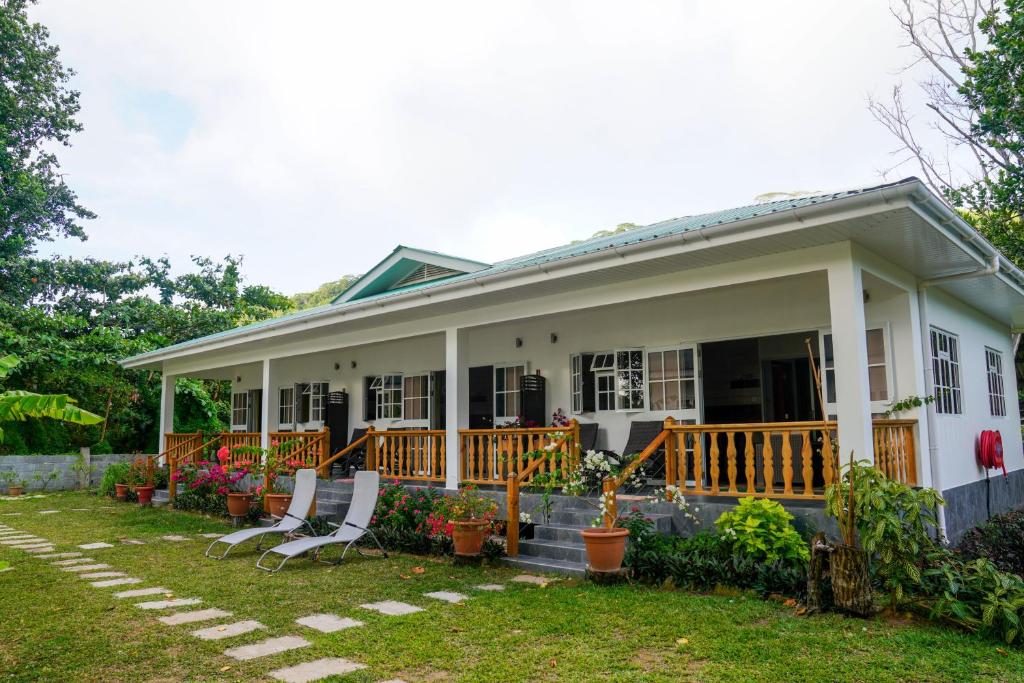 a white house with two white chairs in the yard at Villa Charette-Self Catering Villas in La Digue