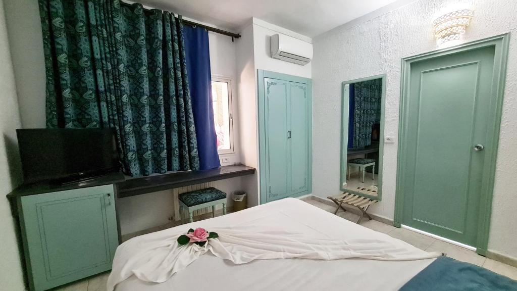 a bedroom with a bed and a tv and a window at Hotel Khella in Hammamet