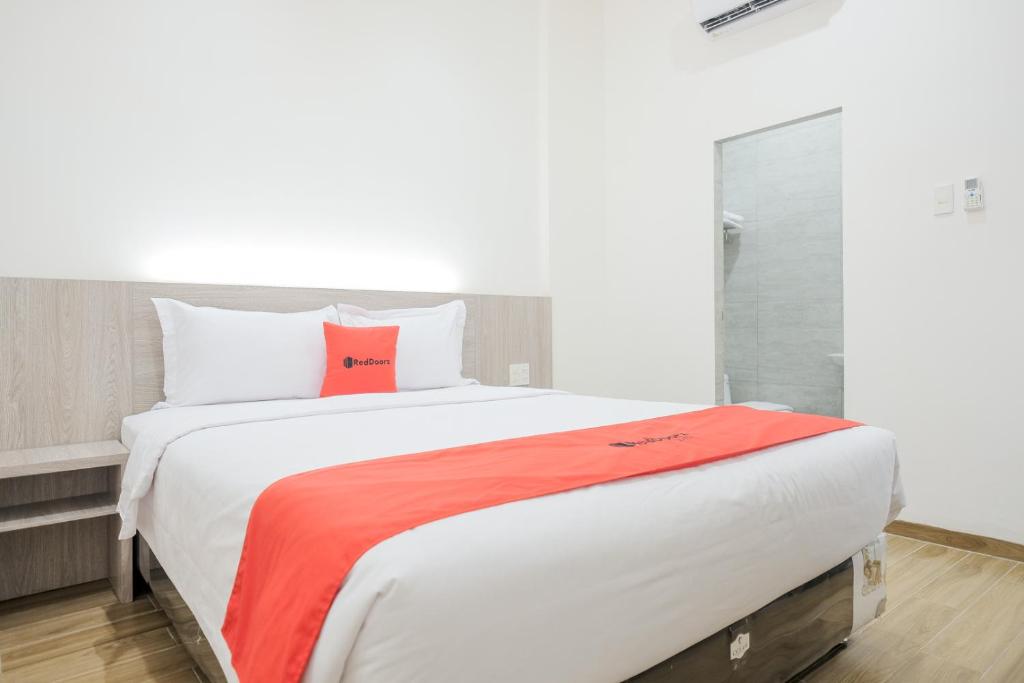 um quarto com uma grande cama branca e uma almofada vermelha em RedDoorz Plus @ Jalan Juanda Medan em Medan