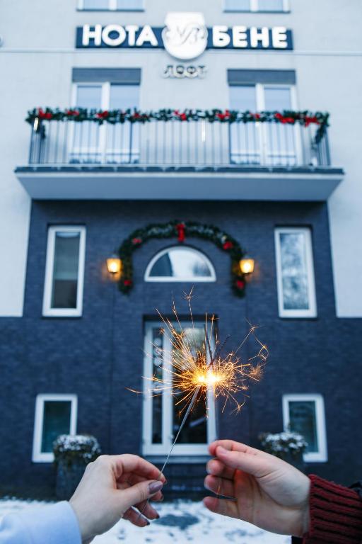 利沃夫Nota Bene Loft的两个人拿着仙女棒站在一栋建筑物前。