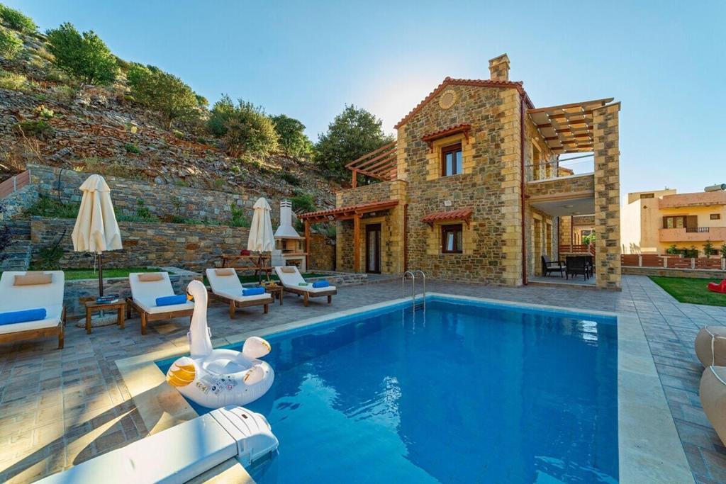 a swimming pool with a swan in front of a house at Faraggi Villas in Zonianá